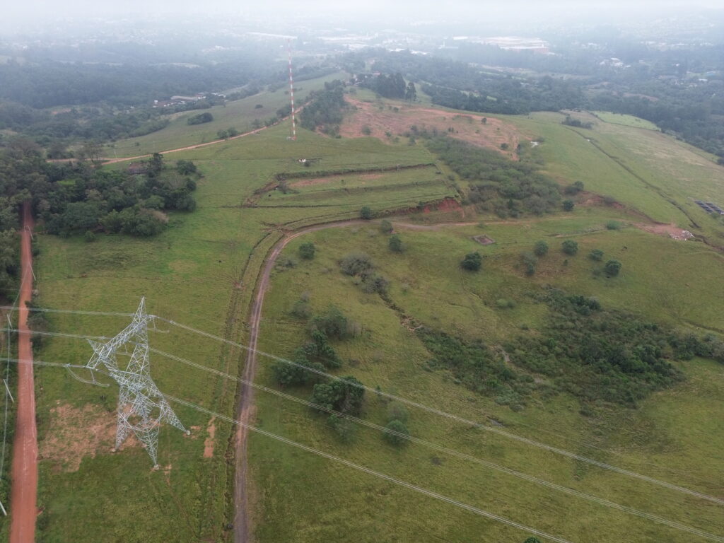 Imagem aérea registrada com Drone: terreno sob análise de viabilidade técnica, mostrando presença de fiação de alta tensão.